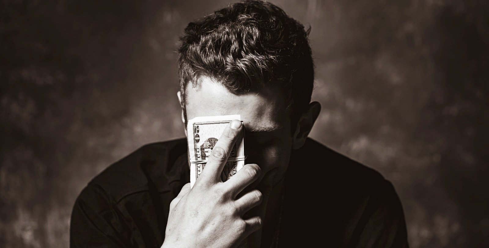 Man upset while holding a stack of money