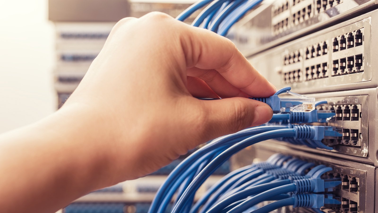 A person plugging in network cables